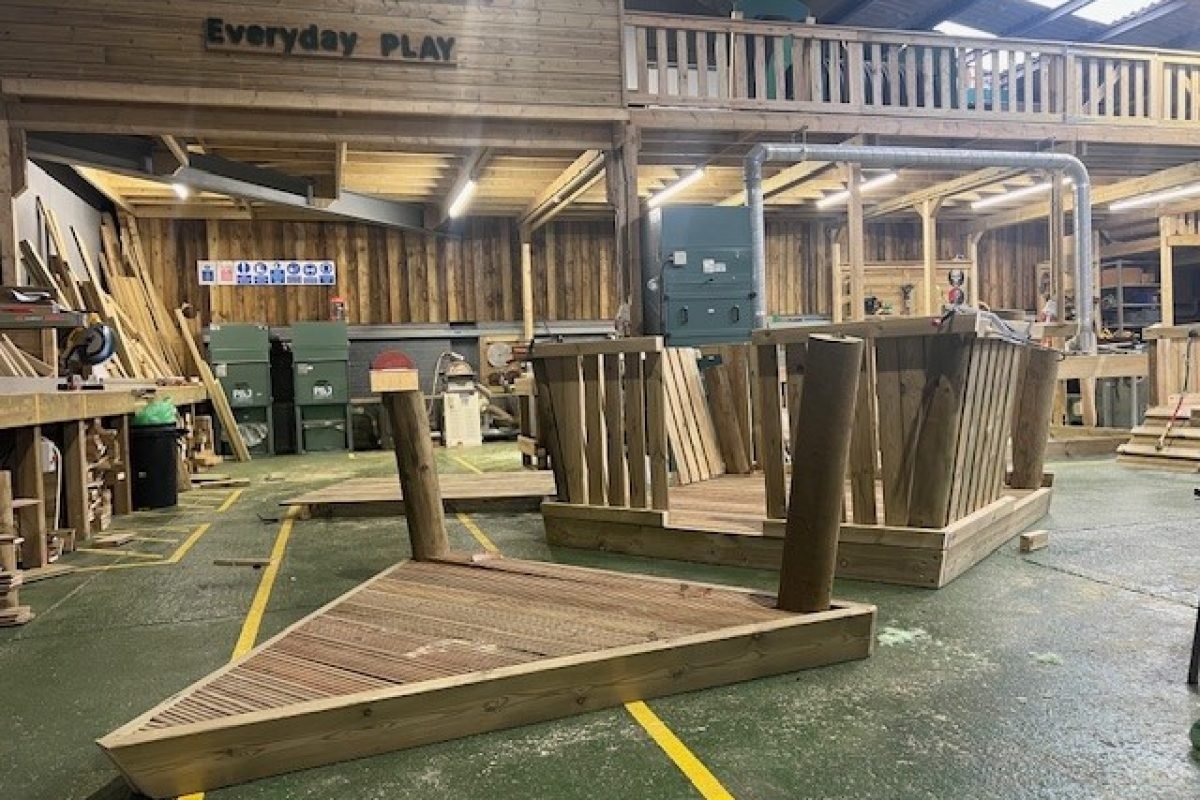 Workshop view of wooden boat playground equipment under construction, showcasing craftsmanship and quality.
