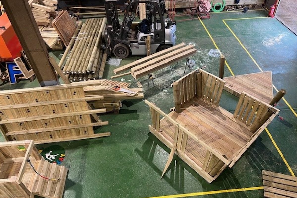 Workshop view of wooden boat playground equipment under construction, showcasing craftsmanship and quality.