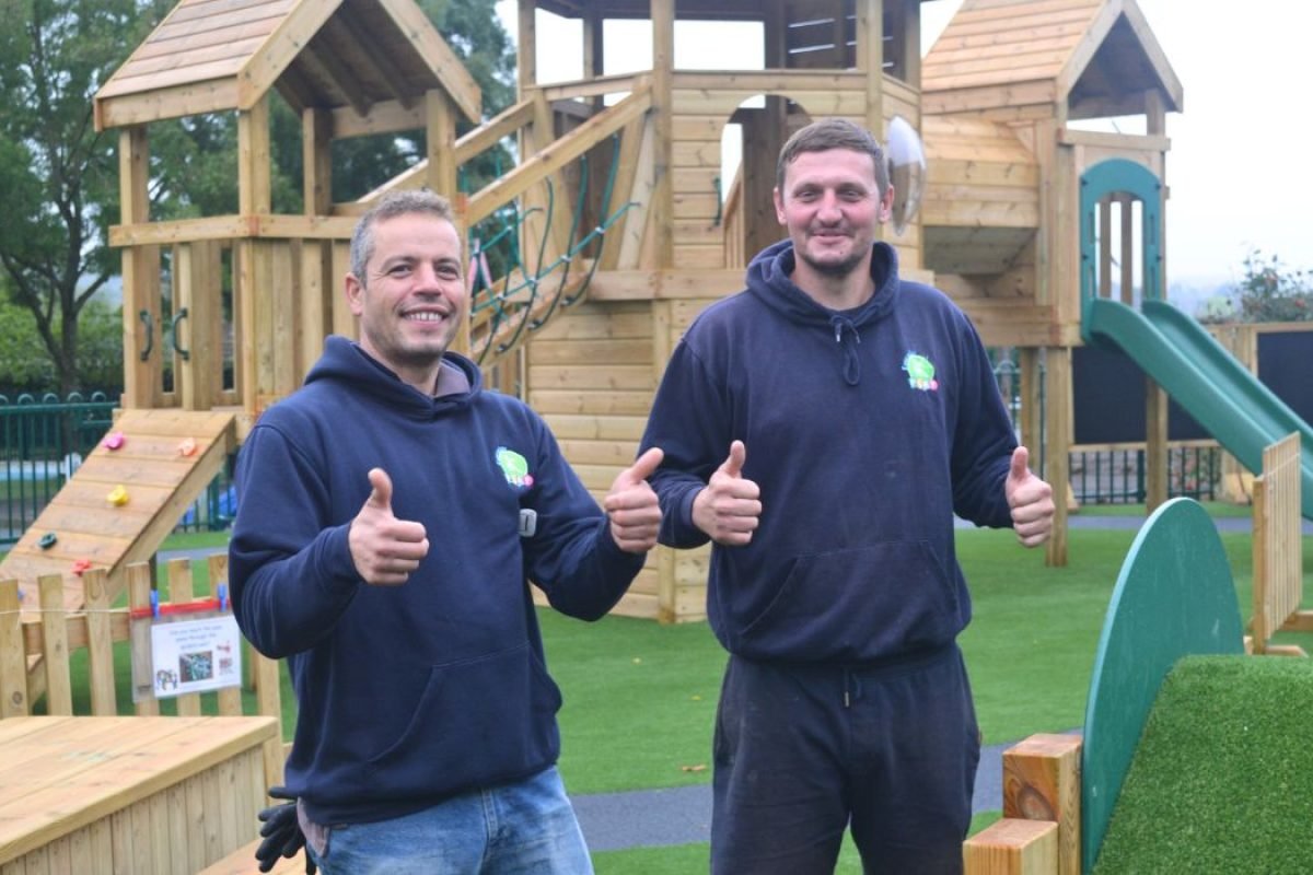 Playground Equipment installers in Kent with thumbs up in front of timber climbing frame and tower